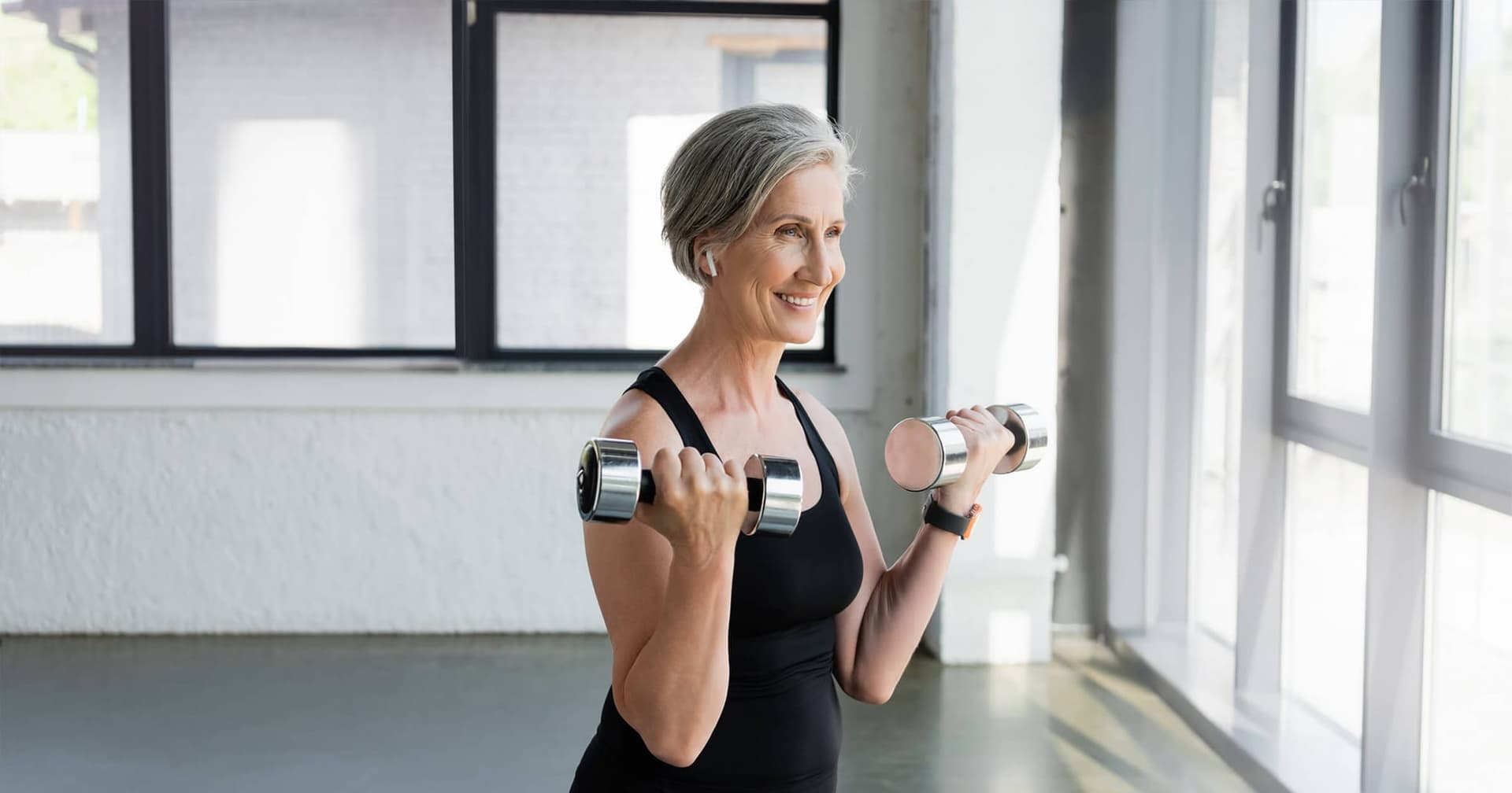A smiling older woman exercising and listening to healtpodcasts